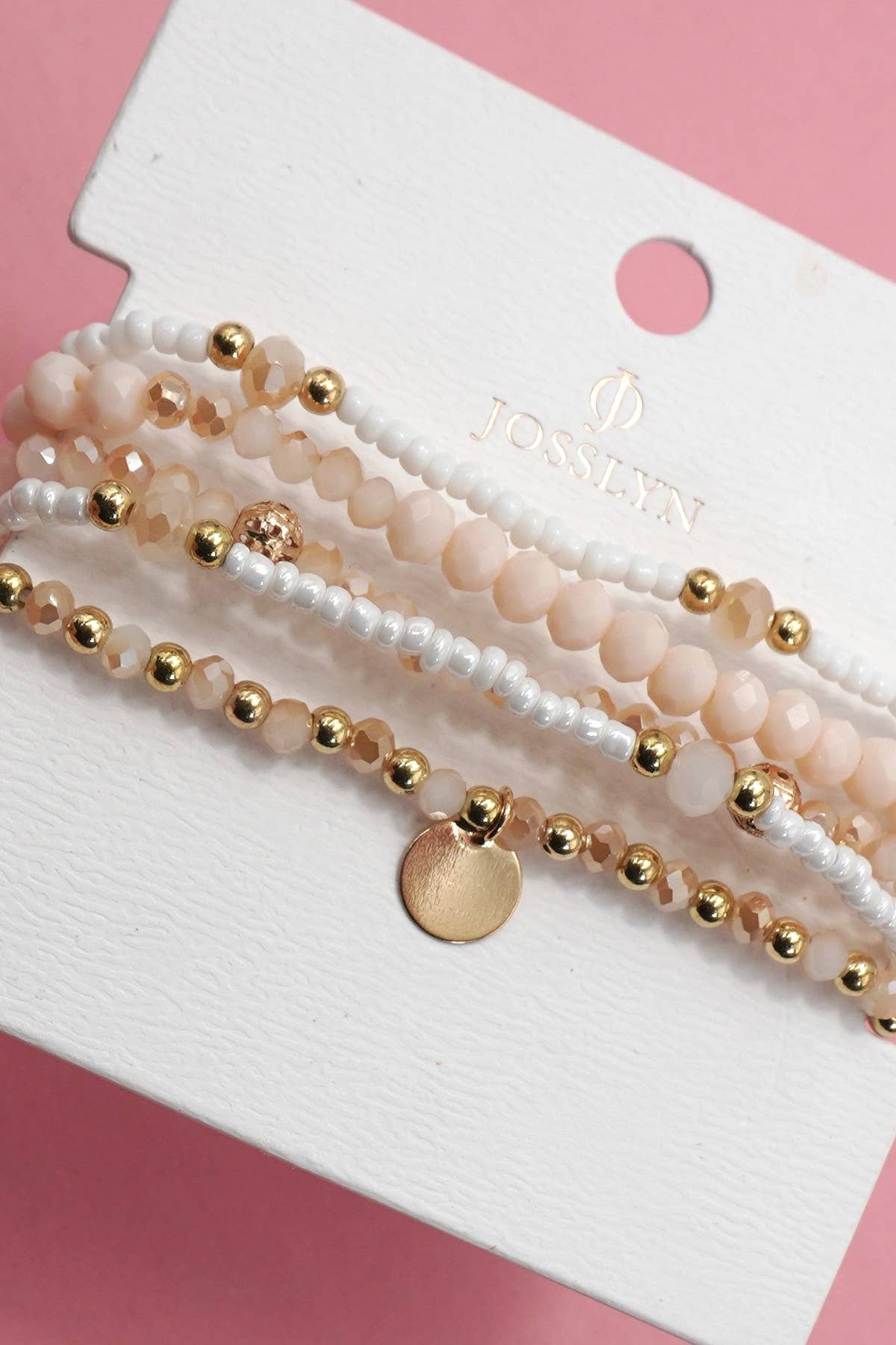 Set of beaded bracelets on a white card with 'Josslyn' branding, against a pink background.