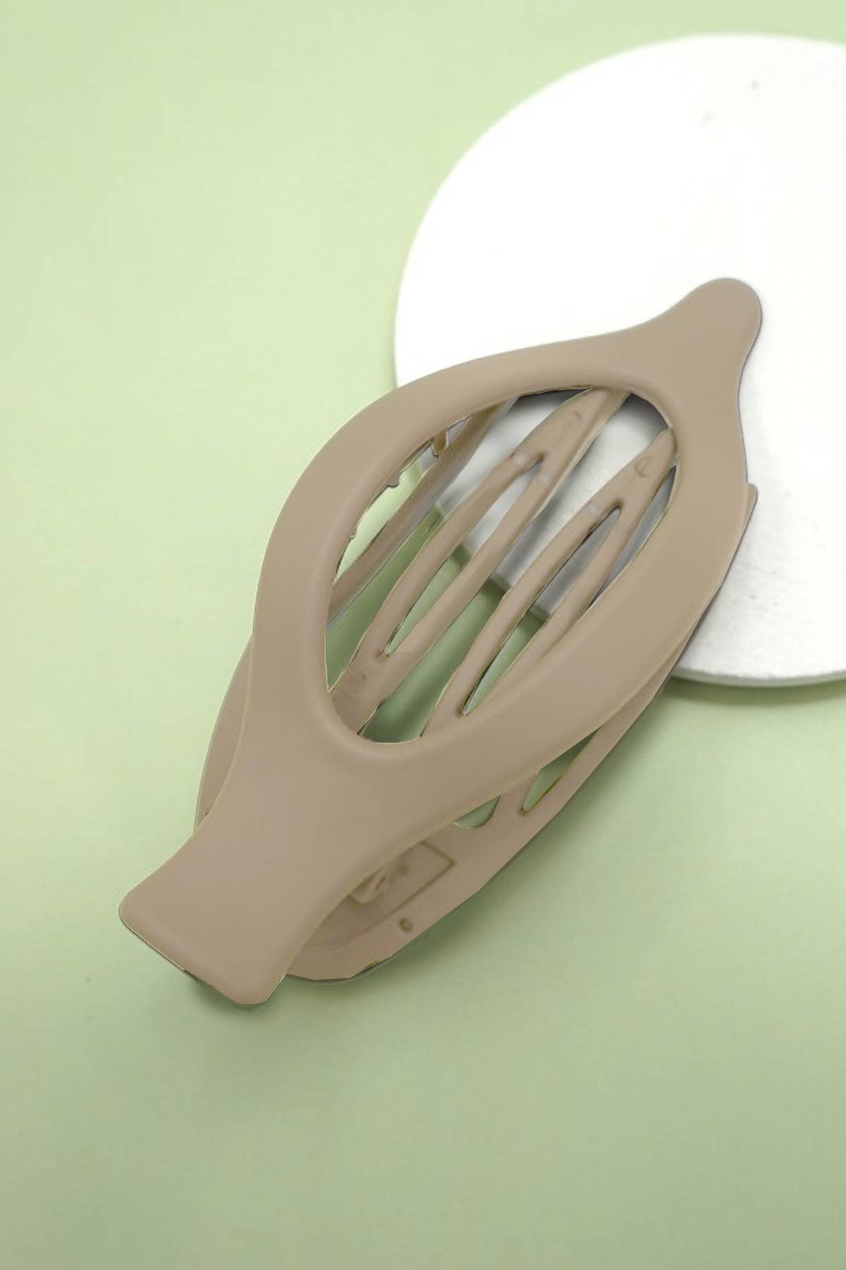 Taupe hair clip on a light green background