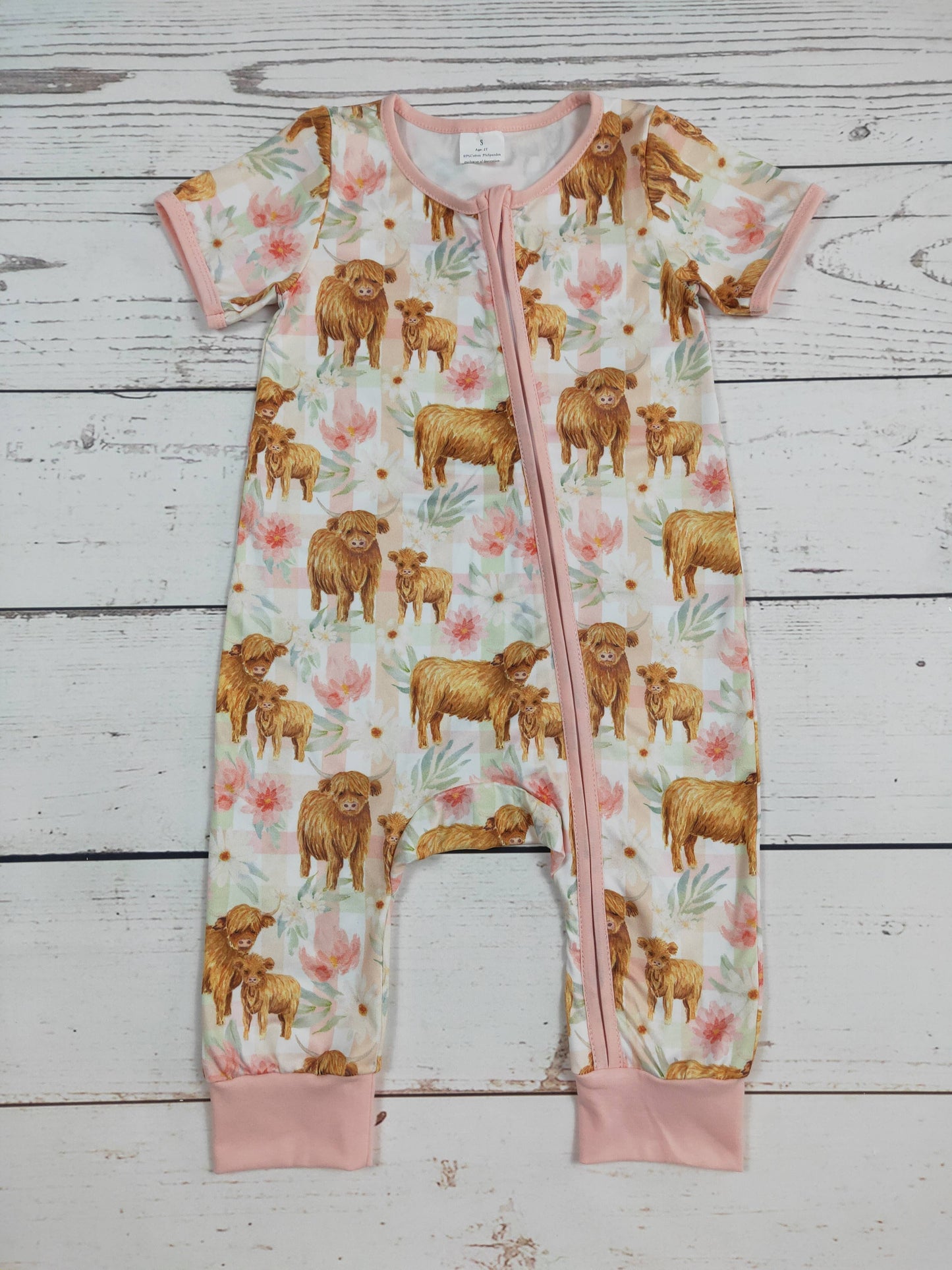 Baby romper with cow and calf pattern on a wooden surface