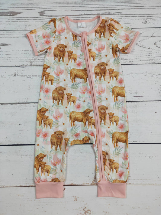 Baby romper with cow and calf pattern on a wooden surface