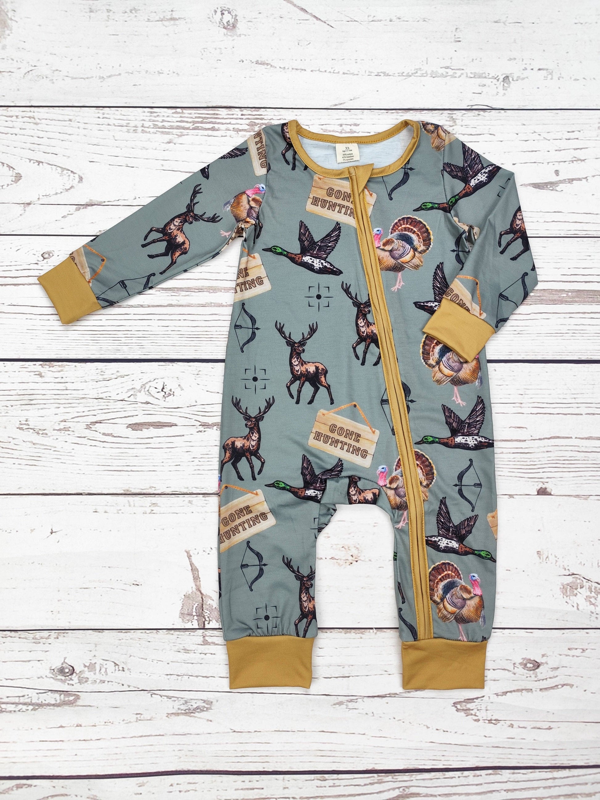 Baby romper with nature-themed print on a wooden surface