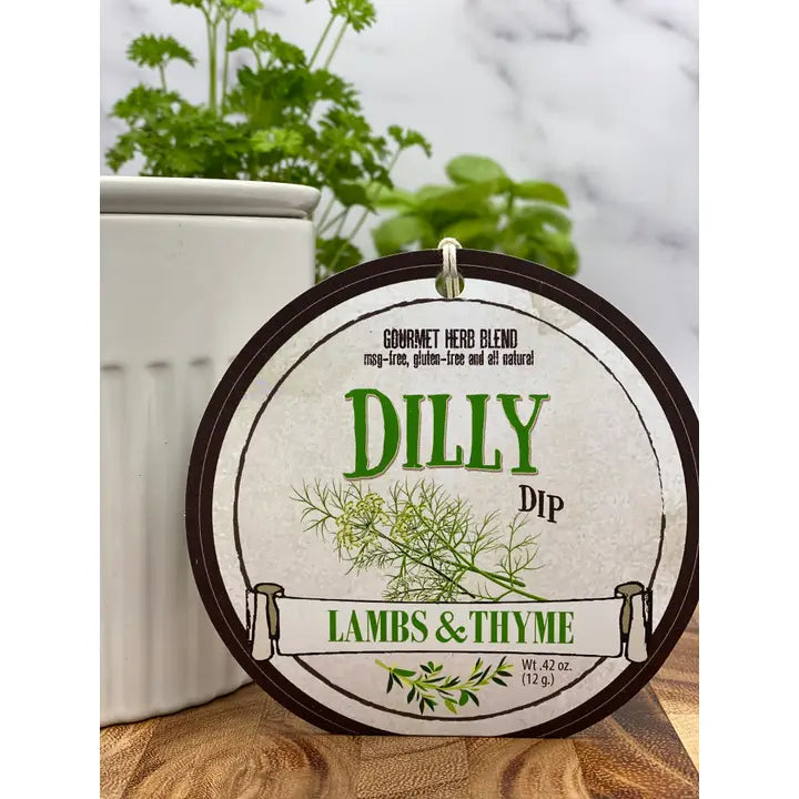 Round label for 'Dilly Dip' by Lambs & Thyme with green text and herbs on a wooden surface.