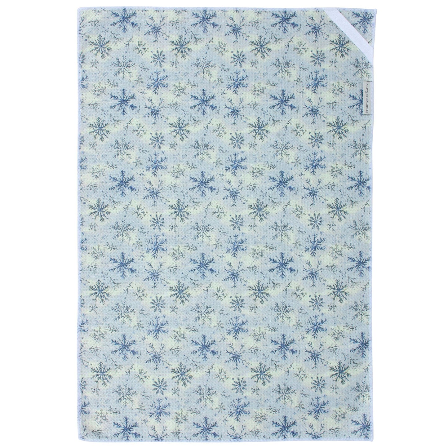 A rectangular kitchen towel, featuring a repeating snowflake pattern in shades of blue and green on a pale cream background. The product is shown flat against a white background with a small white tag visible in the top right corner.