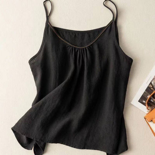 Black sleeveless top on a beige surface with a magazine in the background