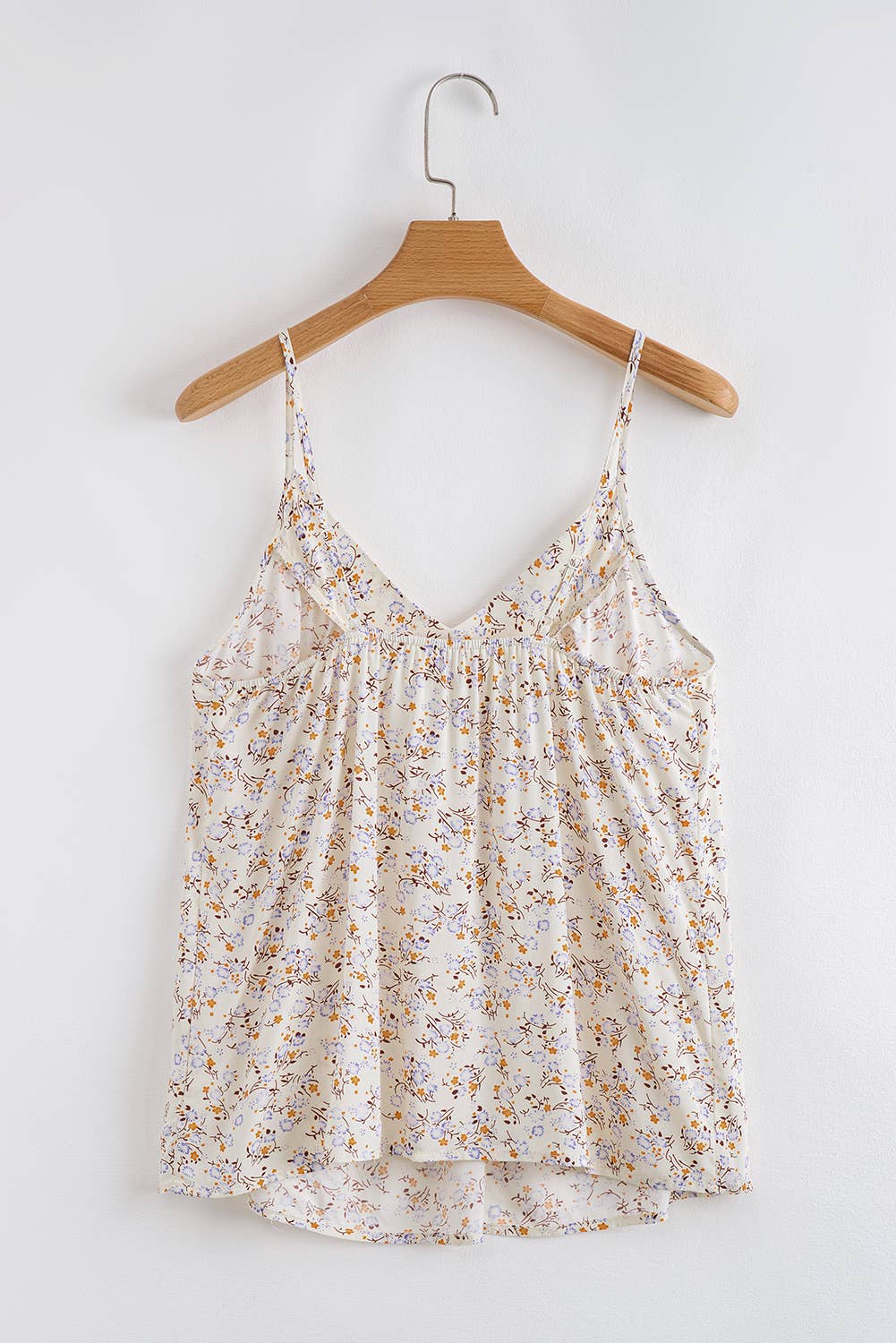 Floral camisole top on a wooden hanger against a white background