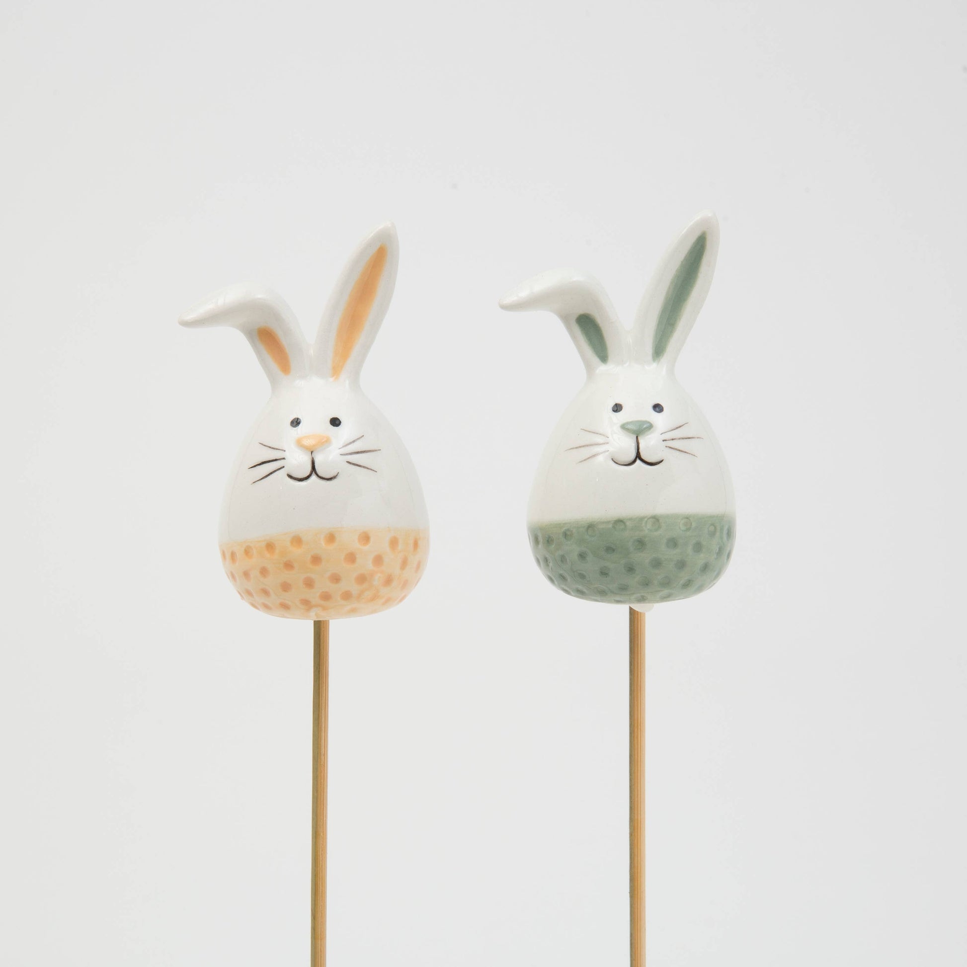 Two rabbit-shaped objects on sticks with textured bodies against a light gray background