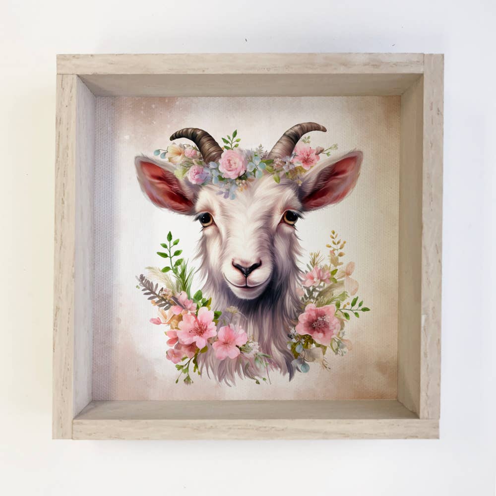 Framed artwork of a goat's head with floral decorations on a light background