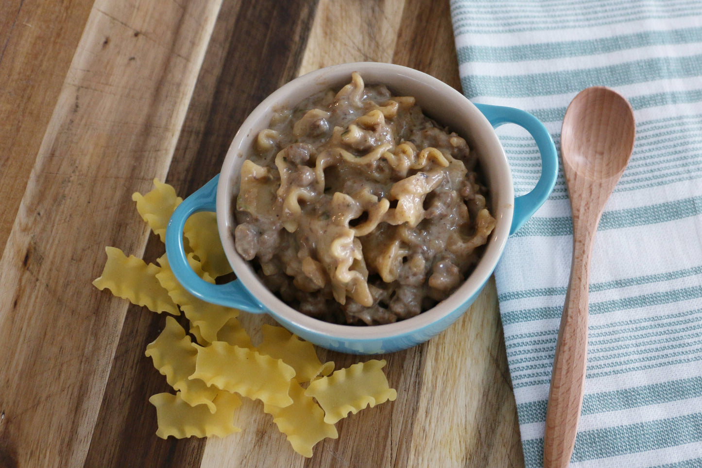 Bowl of pasta with a wooden spoon on a wooden cutting board