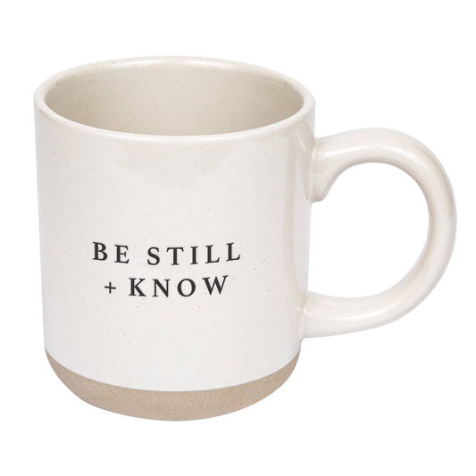 White mug with 'BE STILL + KNOW' text on a white background
