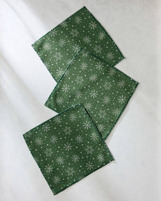 Geometry Dishcloth Set Three green dishcloths with white snowflake patterns on a white background