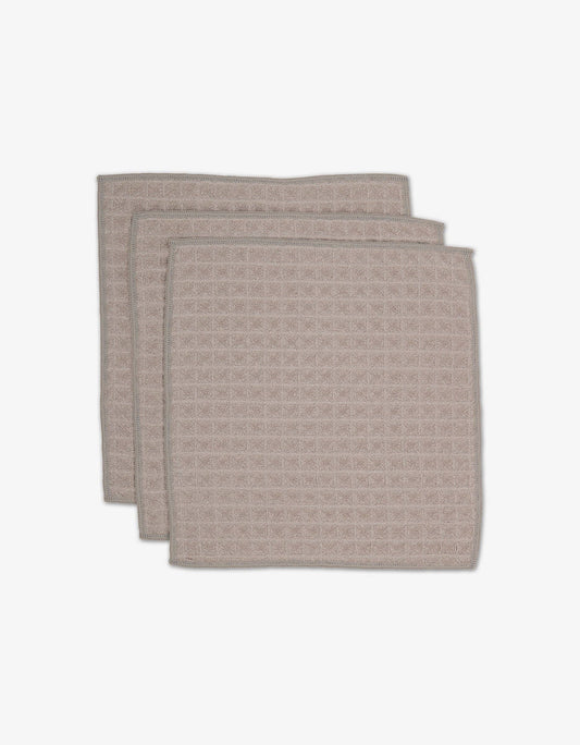 A set of three taupe-colored waffle washcloths stacked on top of each other against a white background.