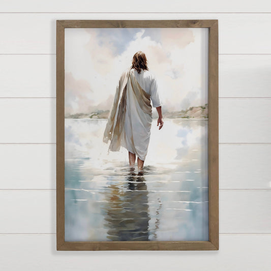 Framed artwork of a person walking on water with a wooden frame.