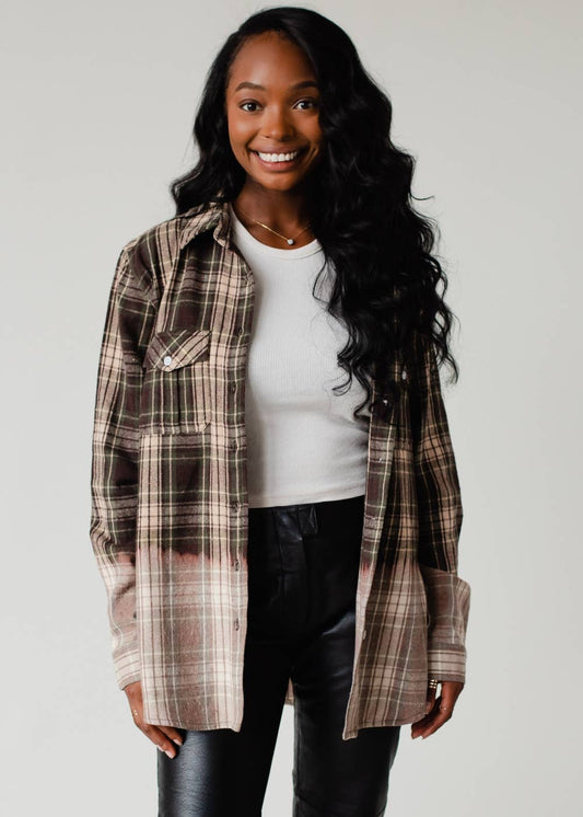 Woman wearing a plaid shirt over a white top and black pants on a plain background