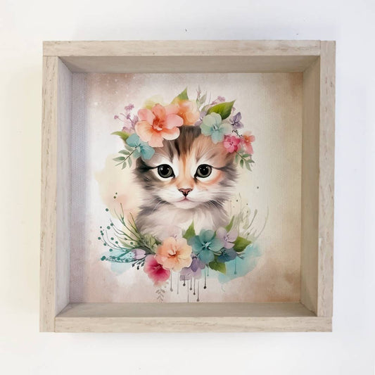 Framed artwork of a kitten with floral decorations on a white background