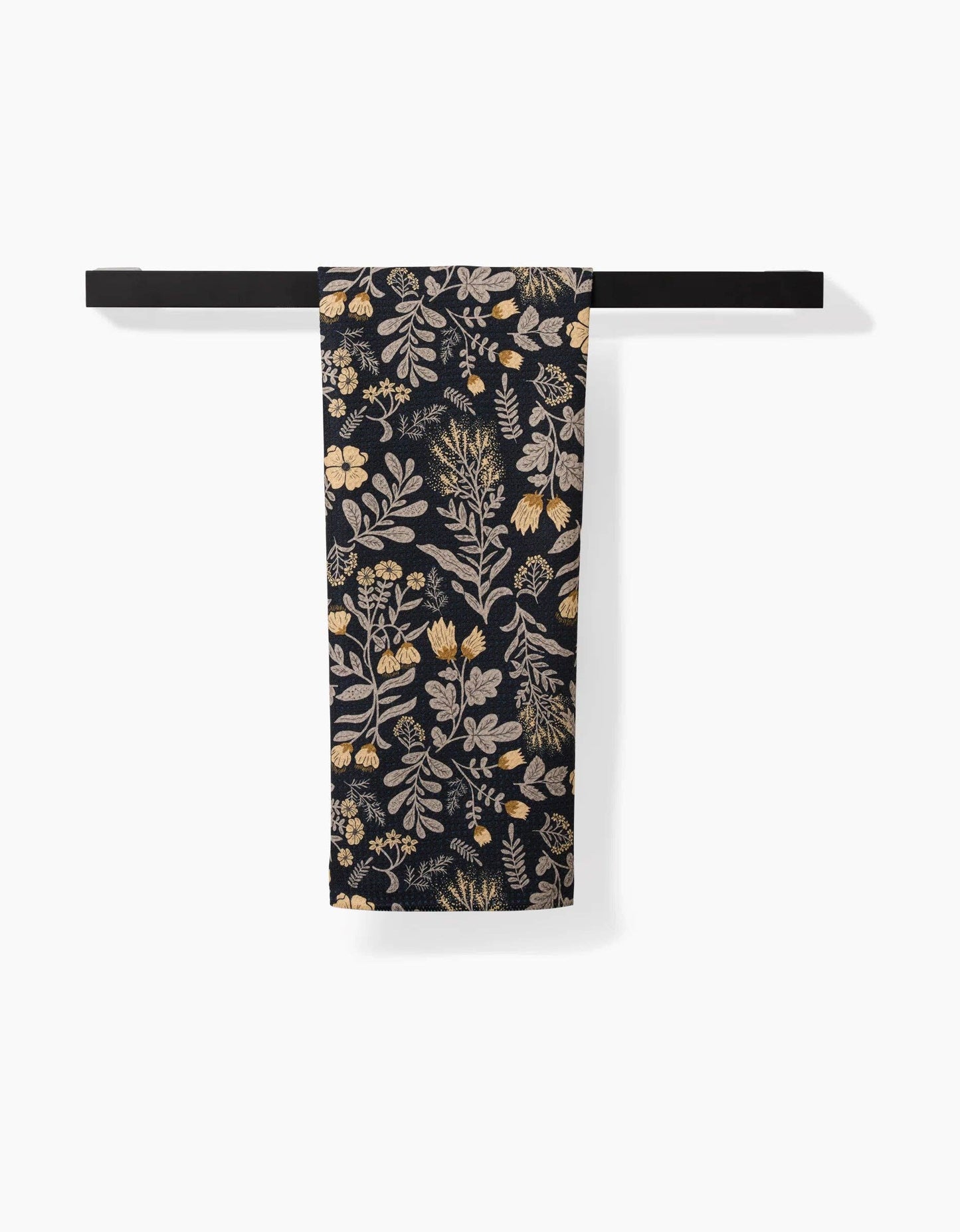 Geometry kitchen tea towel with floral patterned fabric on a black background hanging on a black towel bar with a white background