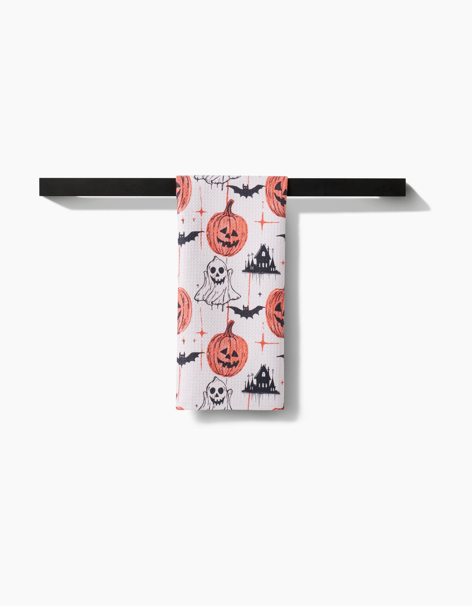 Halloween-themed towel hanging on a black rack against a white background