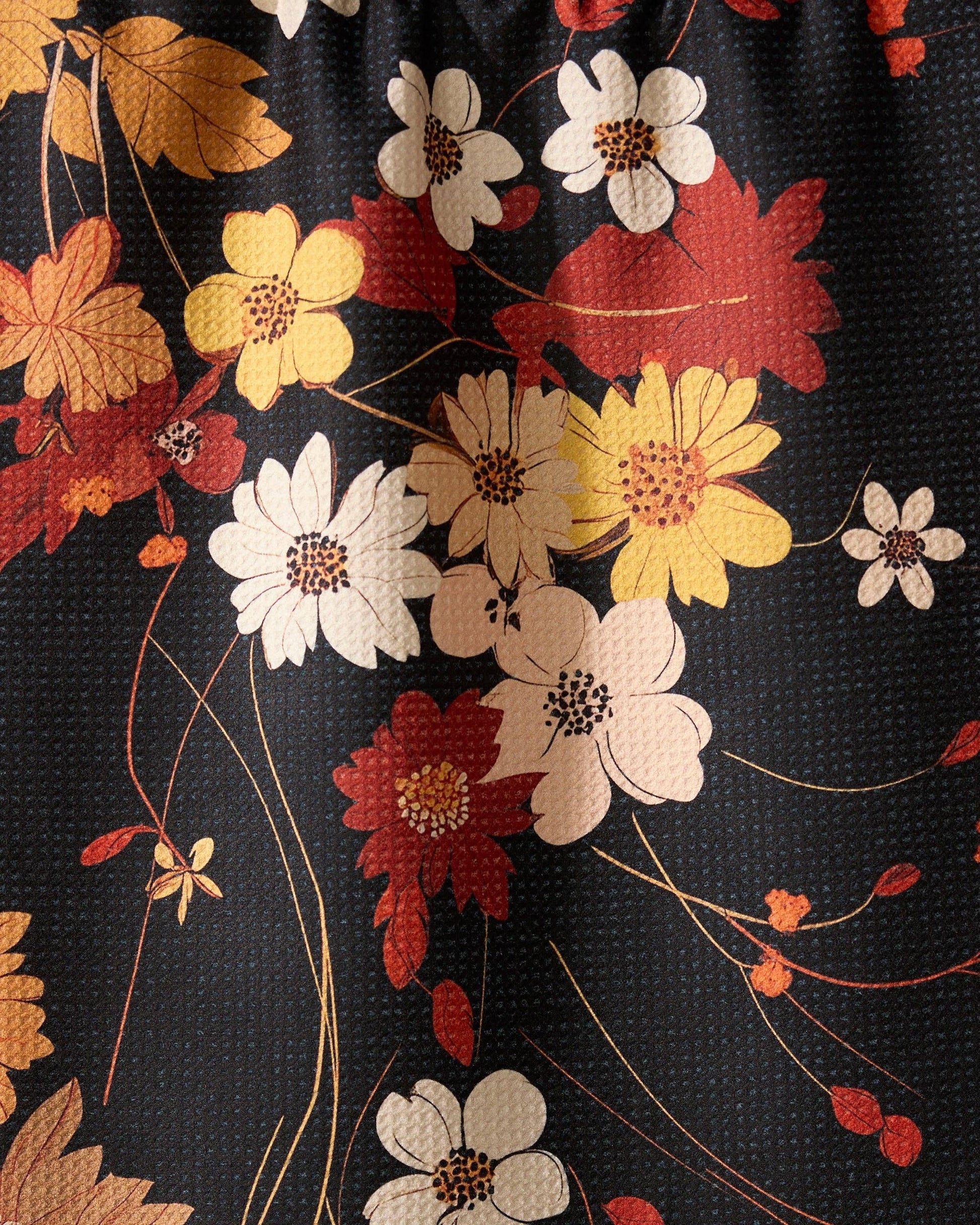 Geometry kitchen tea towel with close-up of floral fabric with red, yellow, and white flowers on a black background