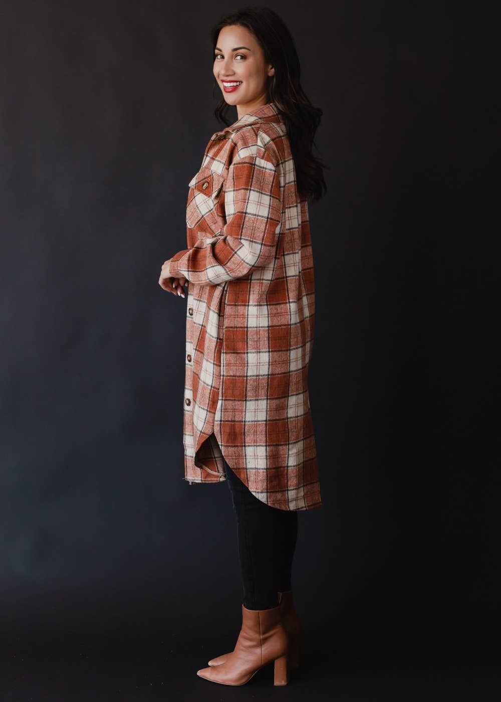 Woman wearing a plaid coat against a black background