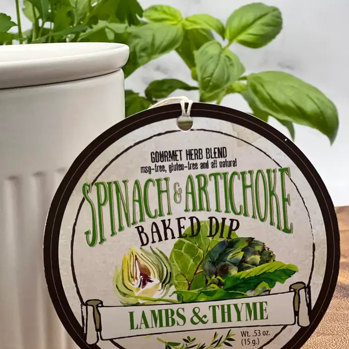 Spinach and Artichoke Baked Dip container with label and basil plant in the background from Lambs & Thyme
